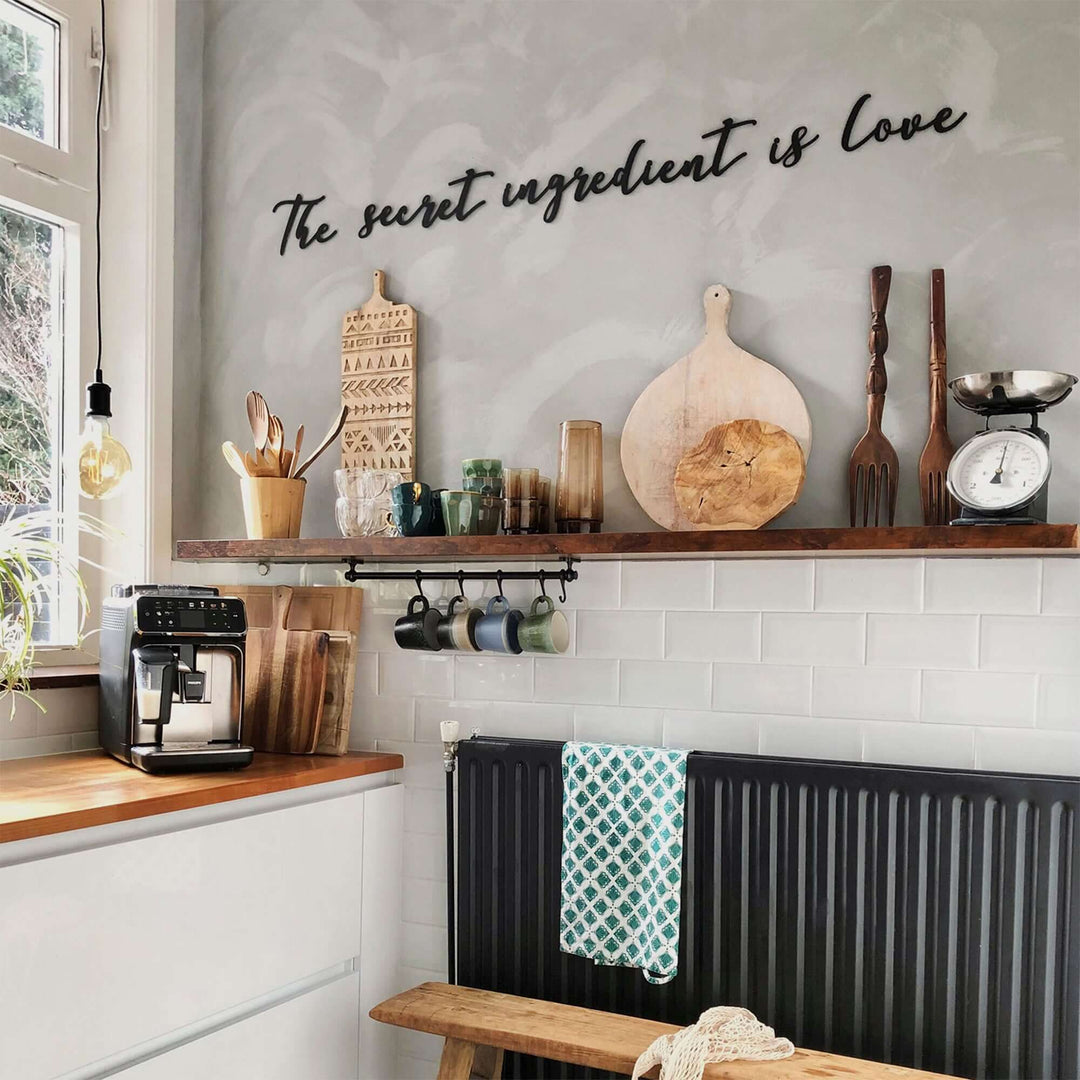 Matte black modern industrial metal wall art reading ‘The Secret Ingredient Is Love’—five 2 mm thick steel pieces, easy no‑drill adhesive installation, customizable layout for kitchen or outdoor décor