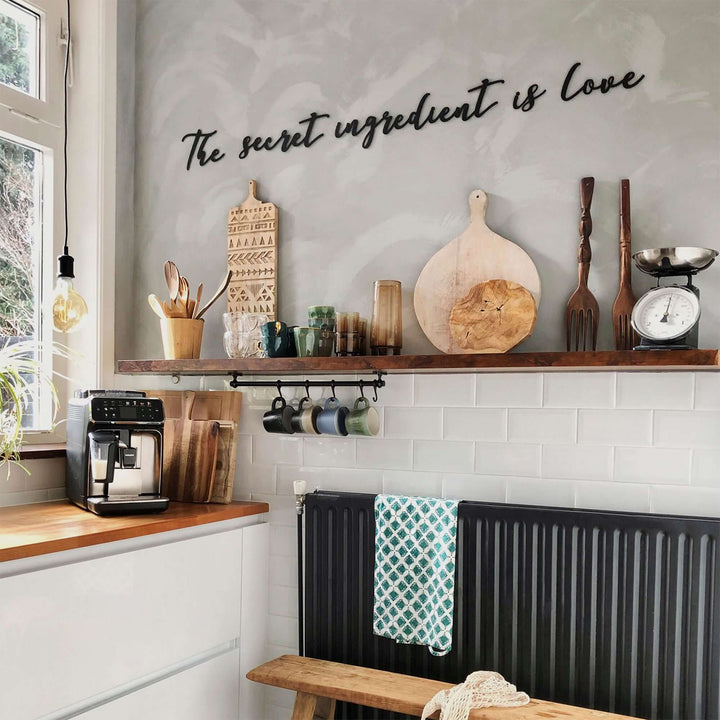Matte black modern industrial metal wall art reading ‘The Secret Ingredient Is Love’—five 2 mm thick steel pieces, easy no‑drill adhesive installation, customizable layout for kitchen or outdoor décor